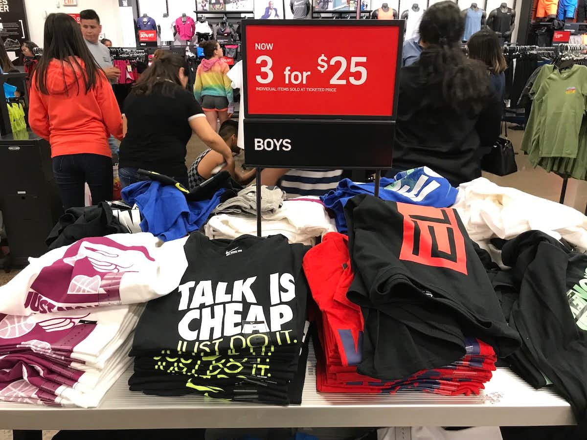 A table displaying boys Nike t-shirts with a sale sign that reads, "Now 3 for $25