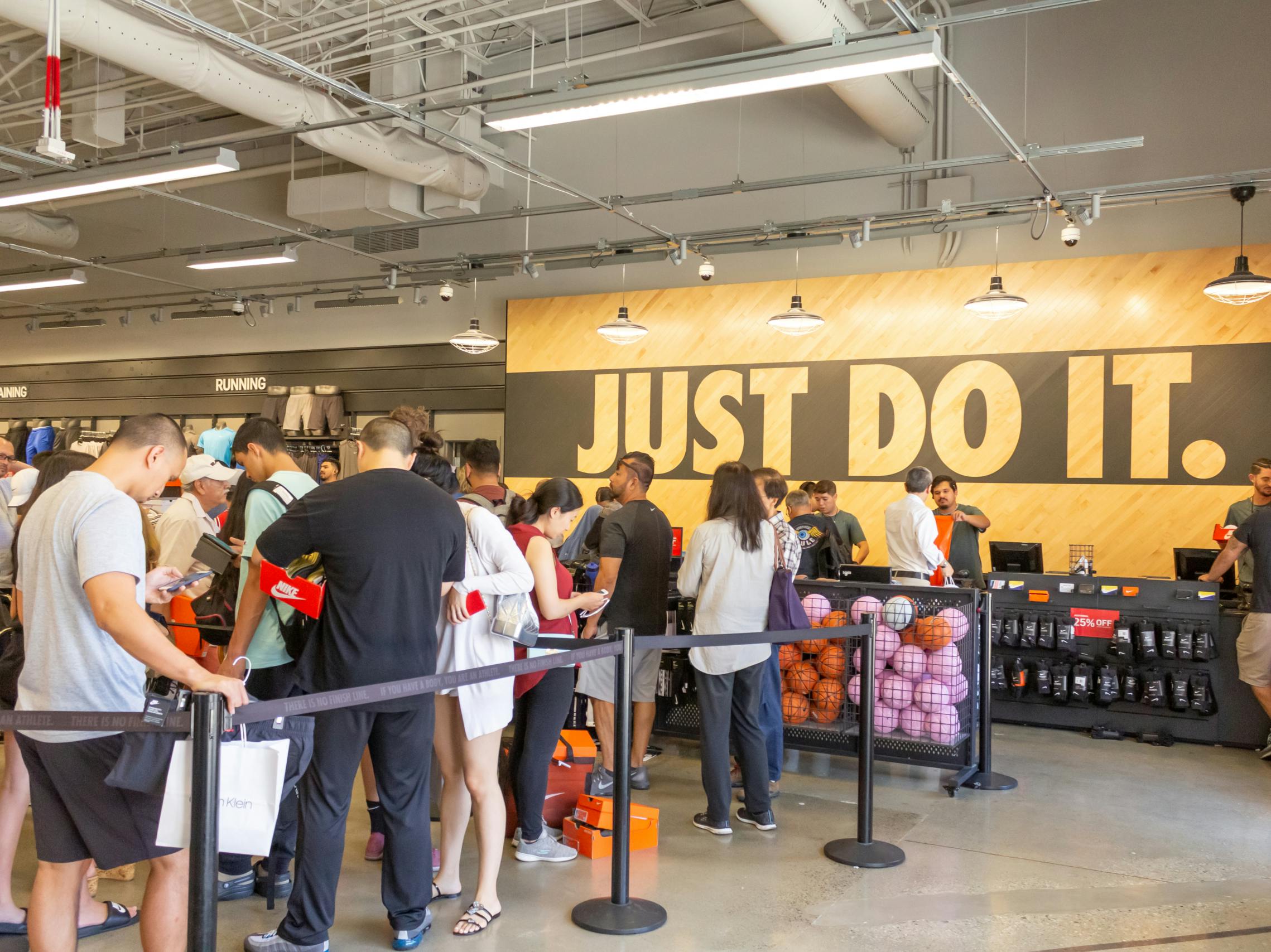 A long line of customers in front of the checkout counter at a Nike store.