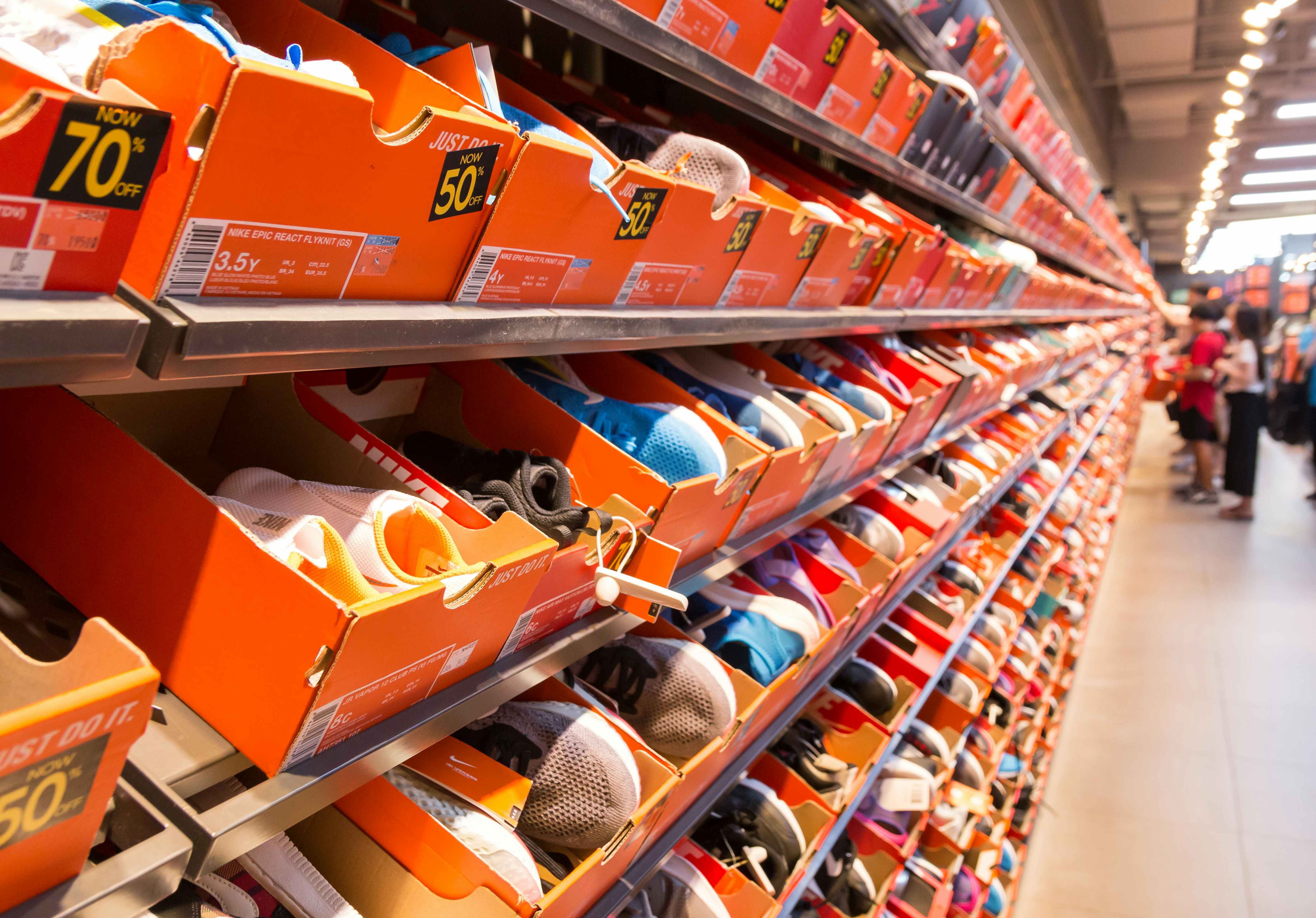 A wall of shoes in orange shoe boxes in the clearance section of a Nike Factory Store.