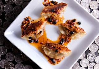 Dumplings on a plate sitting on a table covered in quarters.