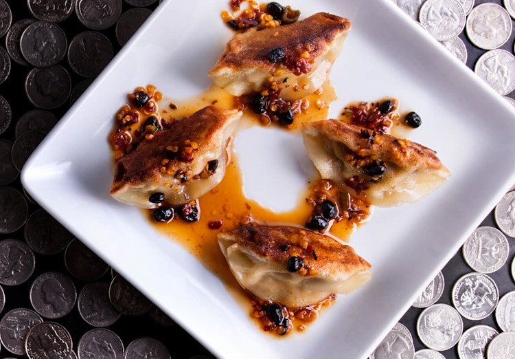 Dumplings on a plate sitting on a table covered in quarters.