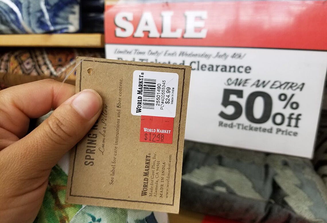 person holding world market tag for something marked down on clarance