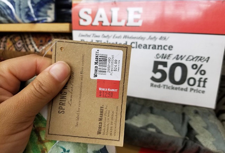person holding world market tag for something marked down on clarance