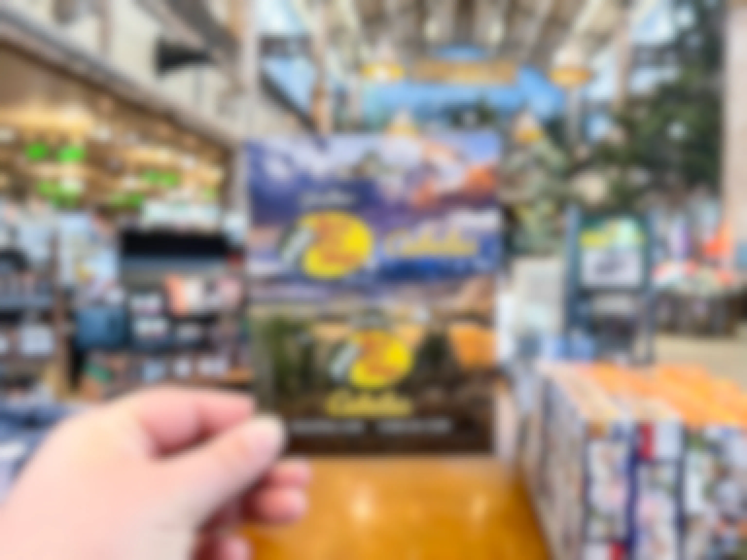 A person's hand holding a Bass Pro Shops/Cabela's gift card inside a Cabela's store.