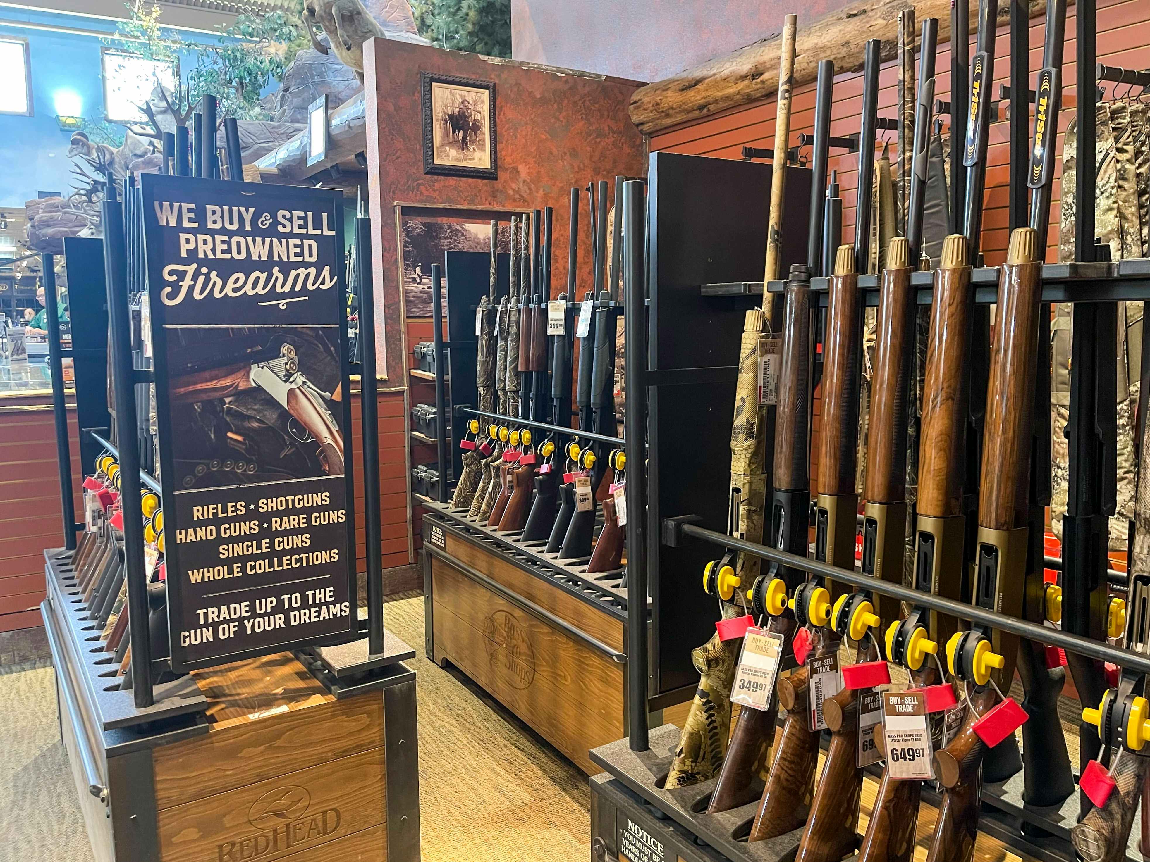 The firearm display inside Cabela's next to a sign that reads, "We buy & sell preowned firearms
