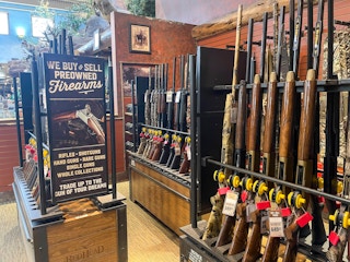 The firearm display inside Cabela's next to a sign that reads, "We buy & sell preowned firearms