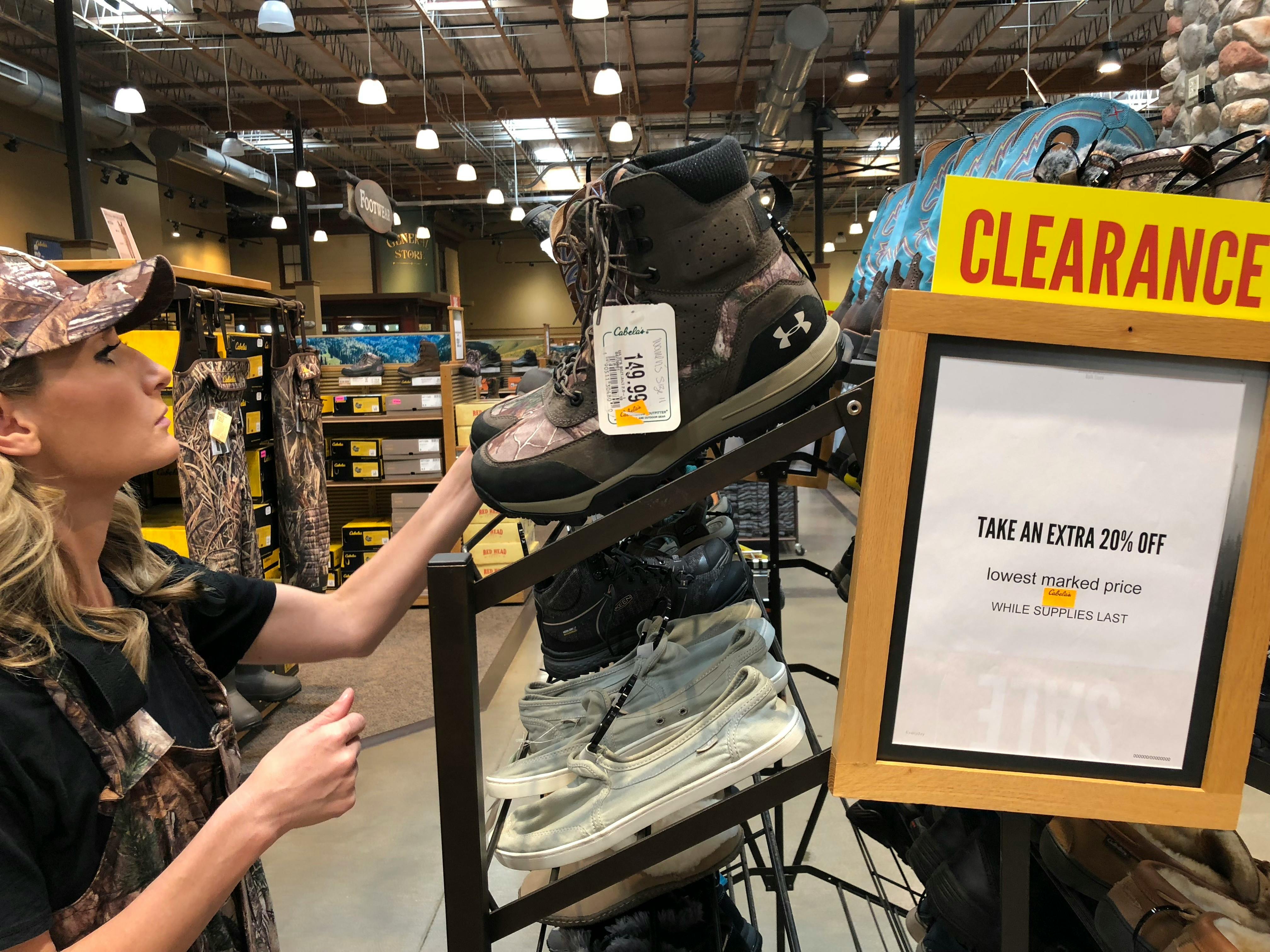 A woman looking at clearance boots on a shelf in Cabela's.