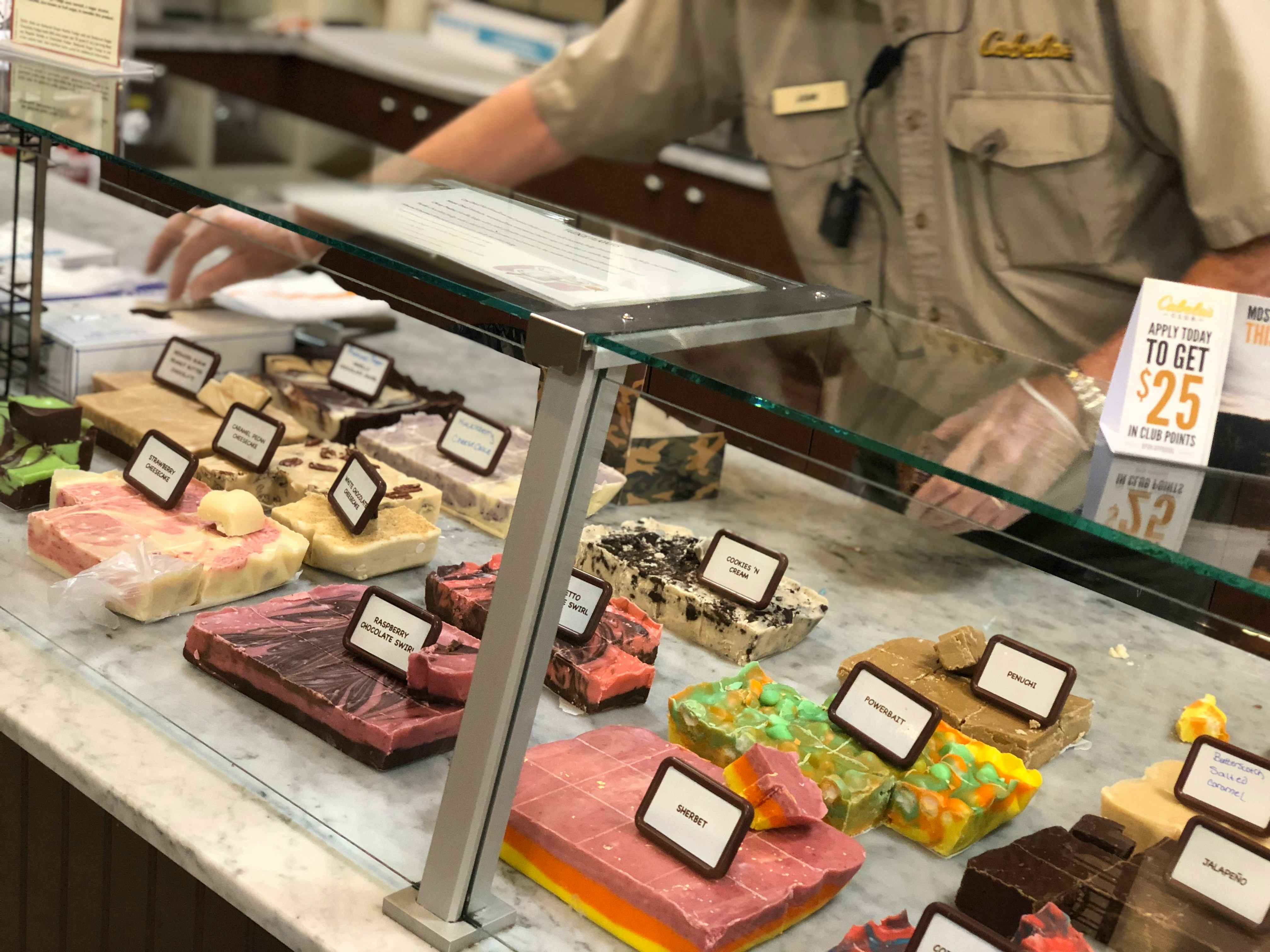 An employee working at the fudge display counter inside Cabela's