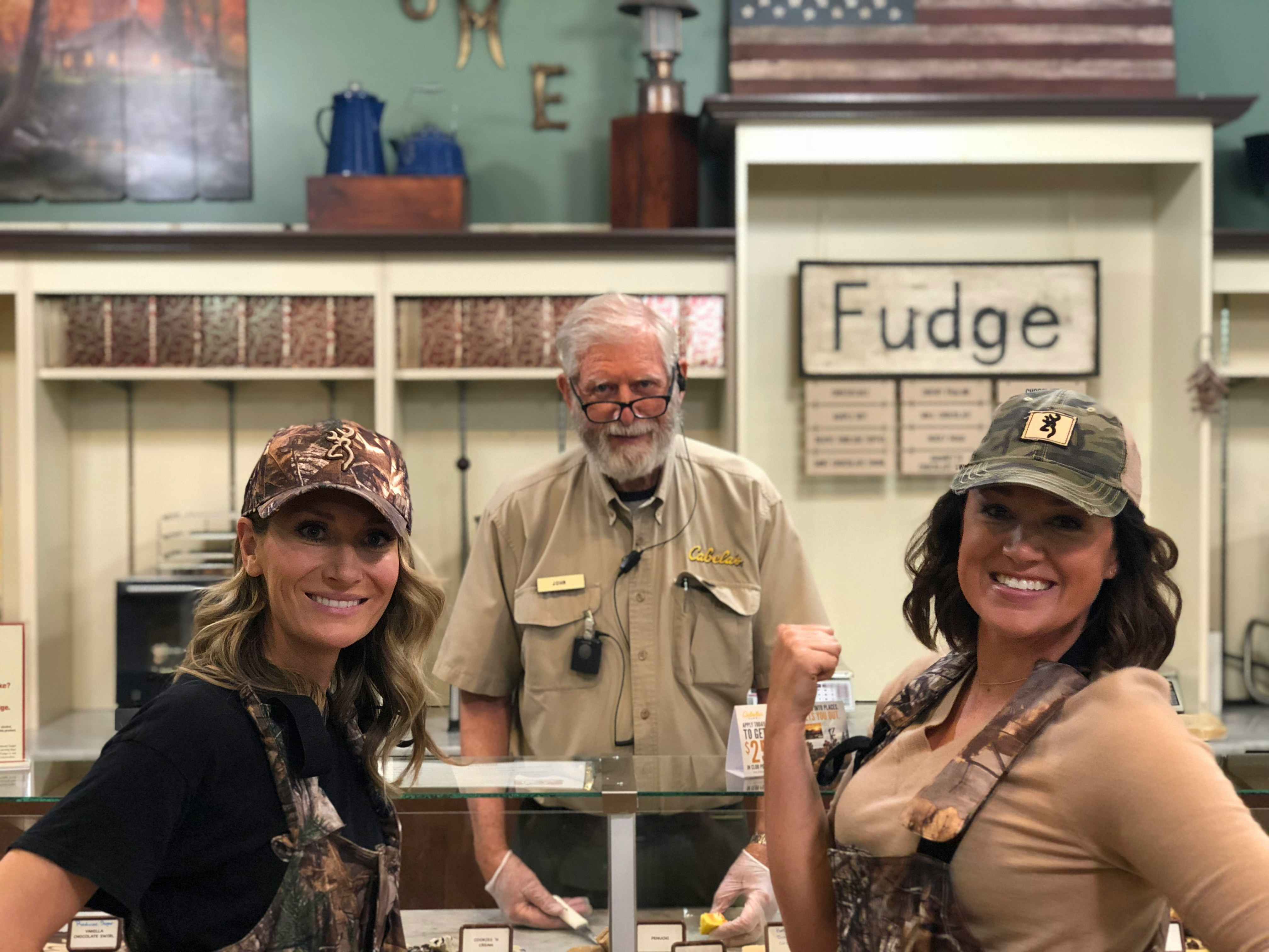 Two women posing with a Cabela's employee at the fudge bar inside Cabela's.