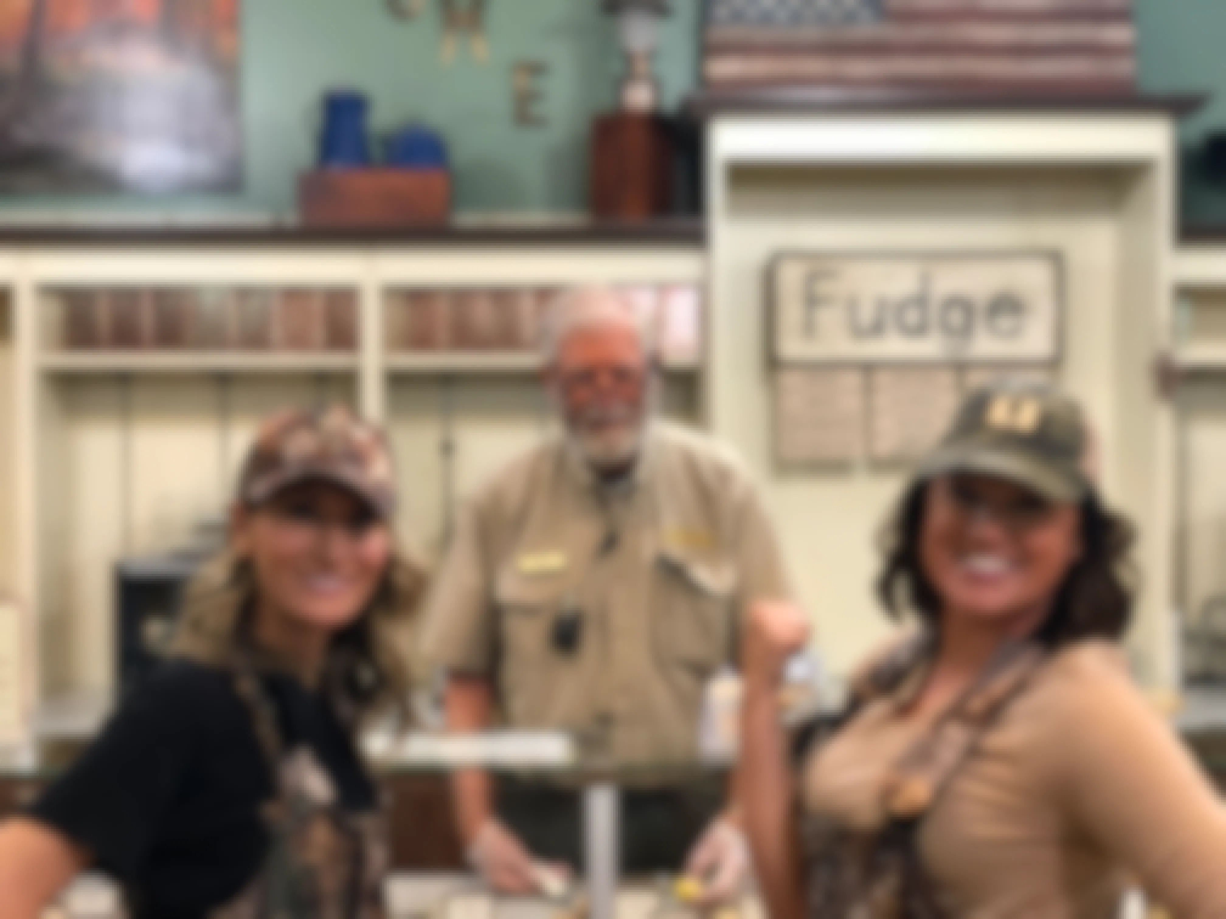 Two women posing with a Cabela's employee at the fudge bar inside Cabela's.