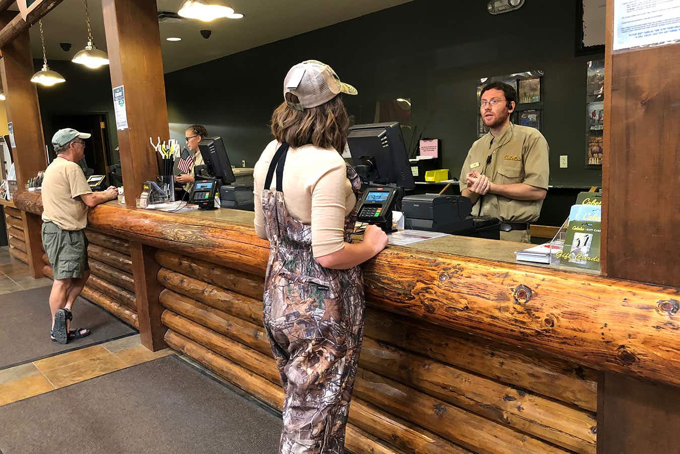 A woman talking to a Cabela's employee at the customer service desk.