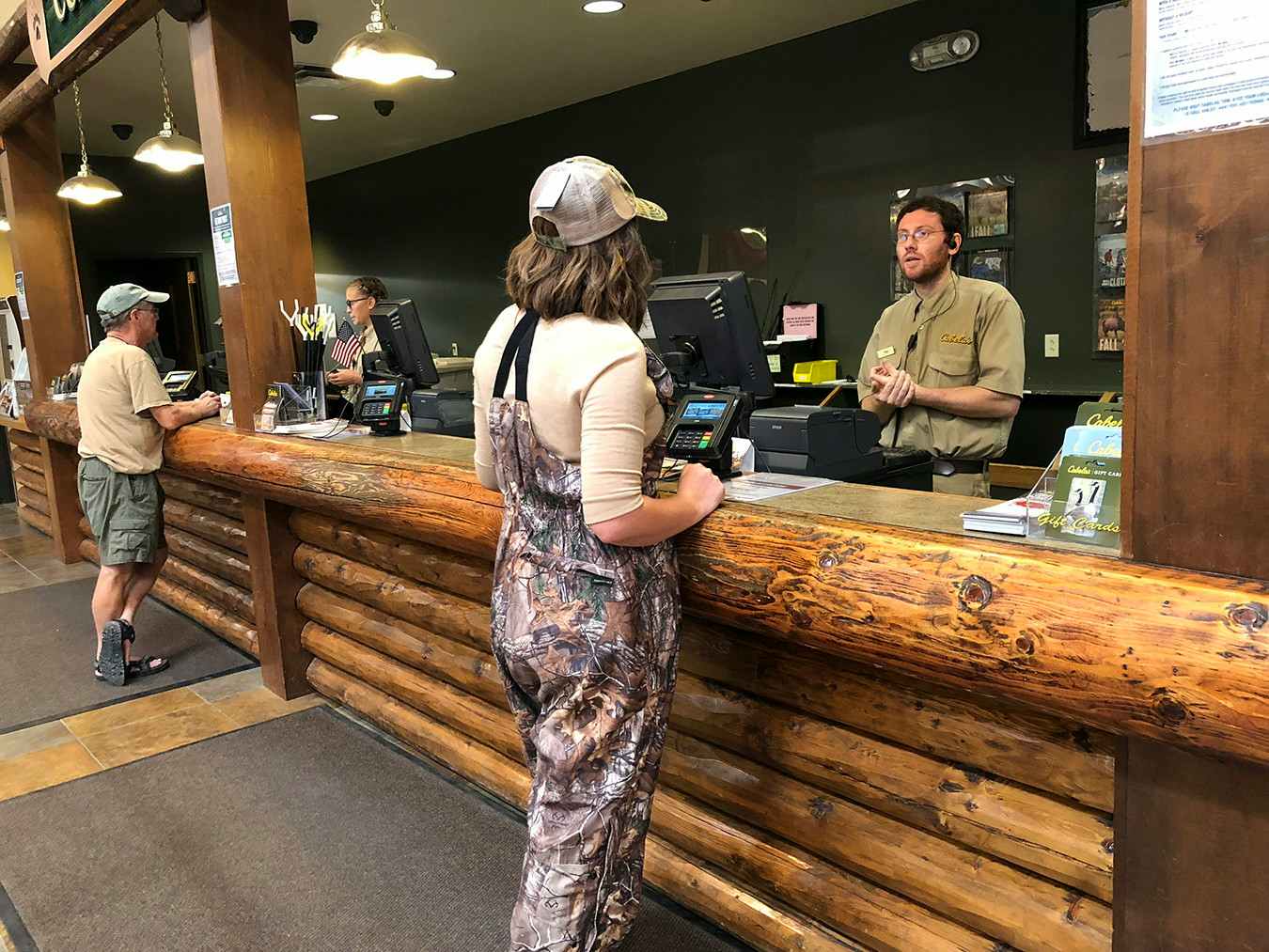 A woman talking to a Cabela's employee at the customer service desk.