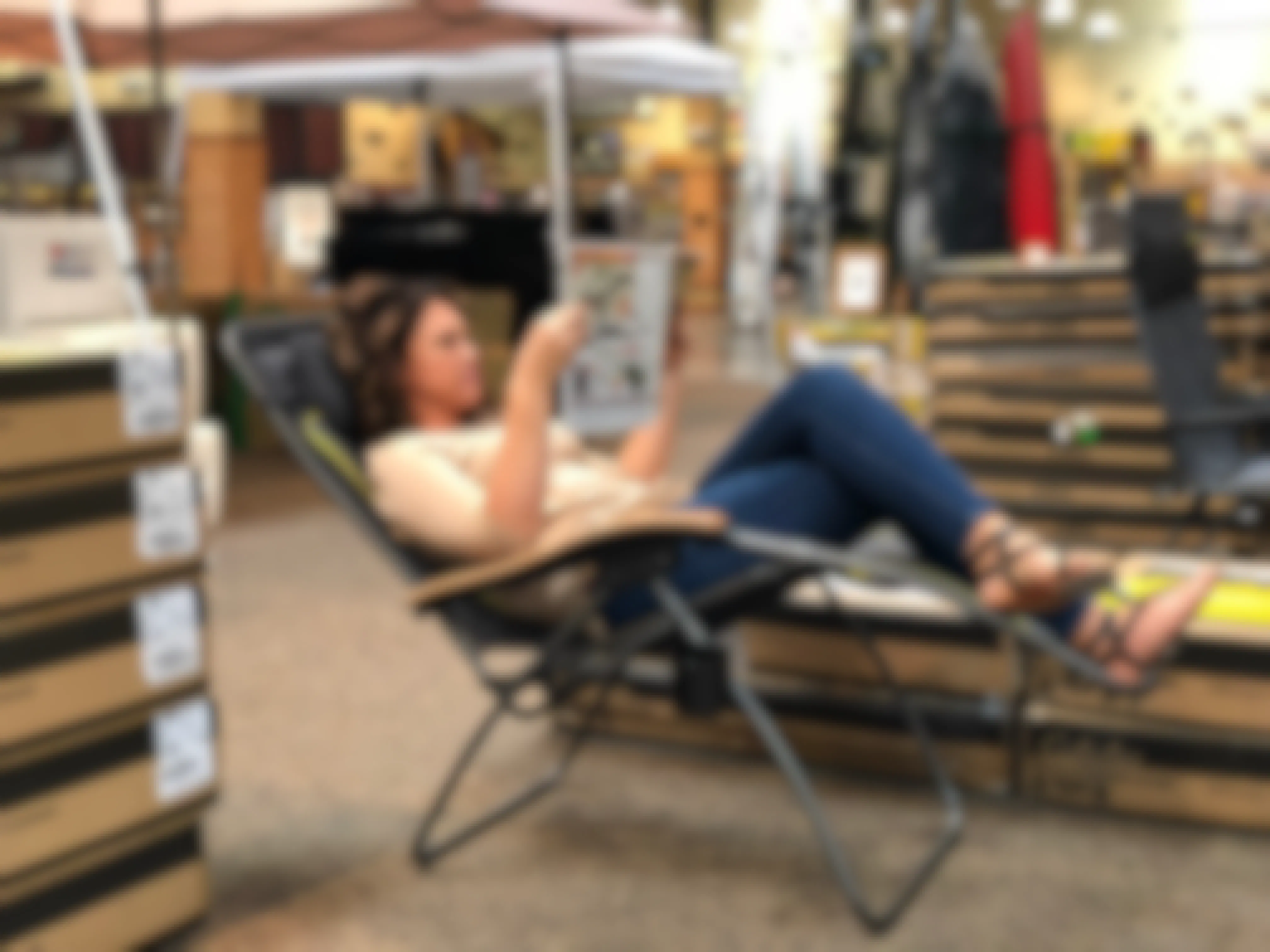 A woman reclining in a chair and looking at an ad book inside Cabela's.