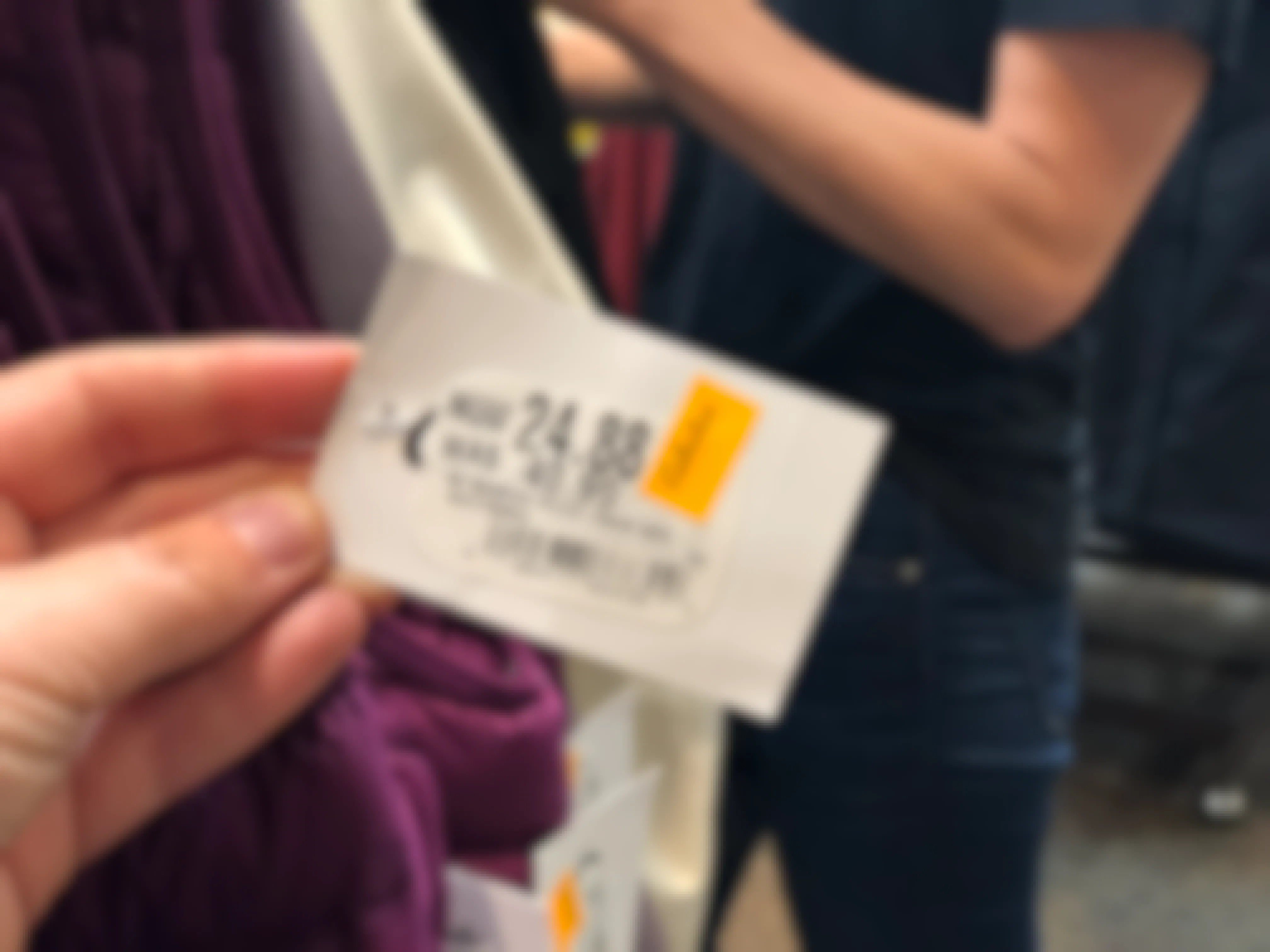 A person's hand holding a price tag of a clearance item at Cabela's.