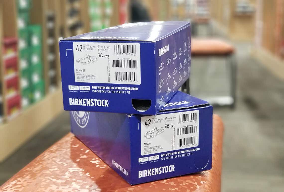 Two Birkenstock shoeboxes stacked on a bench in a shoe store.