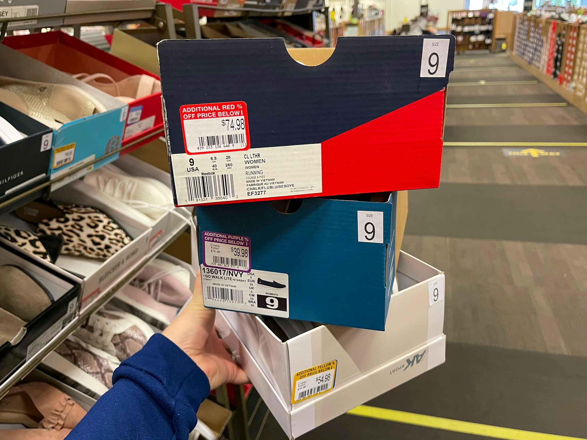 A stack of show boxes with red, purple, and yellow, clearance stickers on them.