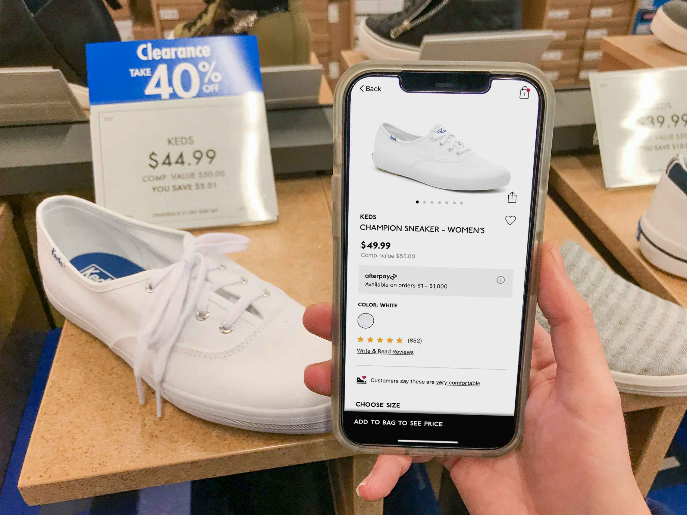 A white shoe on display with a blue sales tag reading "40% off". A cell phone is held next to the shoe and sign with the same shoe on the DSW app, with a regular sales price.