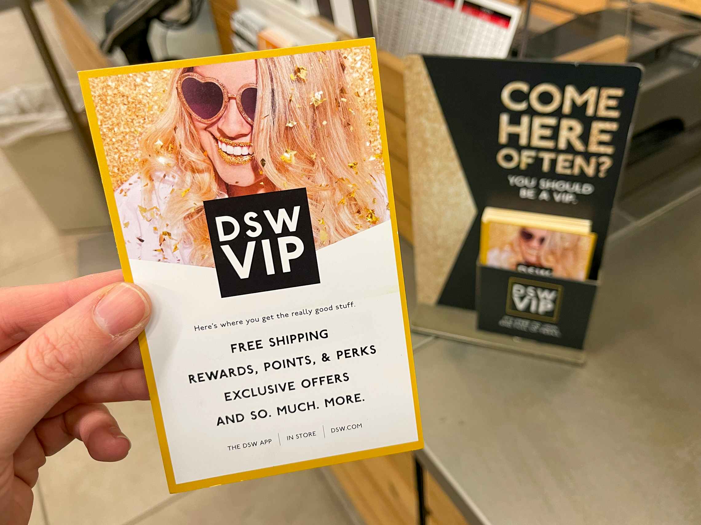 A person holding up a DSW VIP info card near checkout.