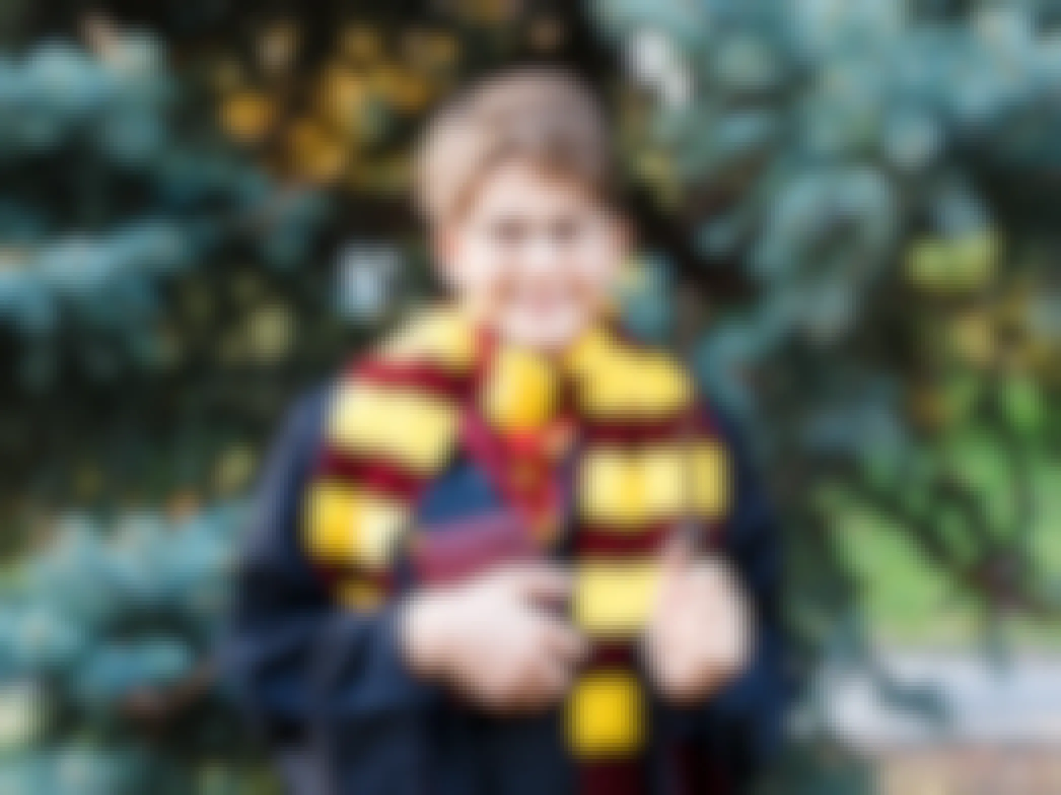A kid dressed as Harry Potter standing outside and holding a wand and books.