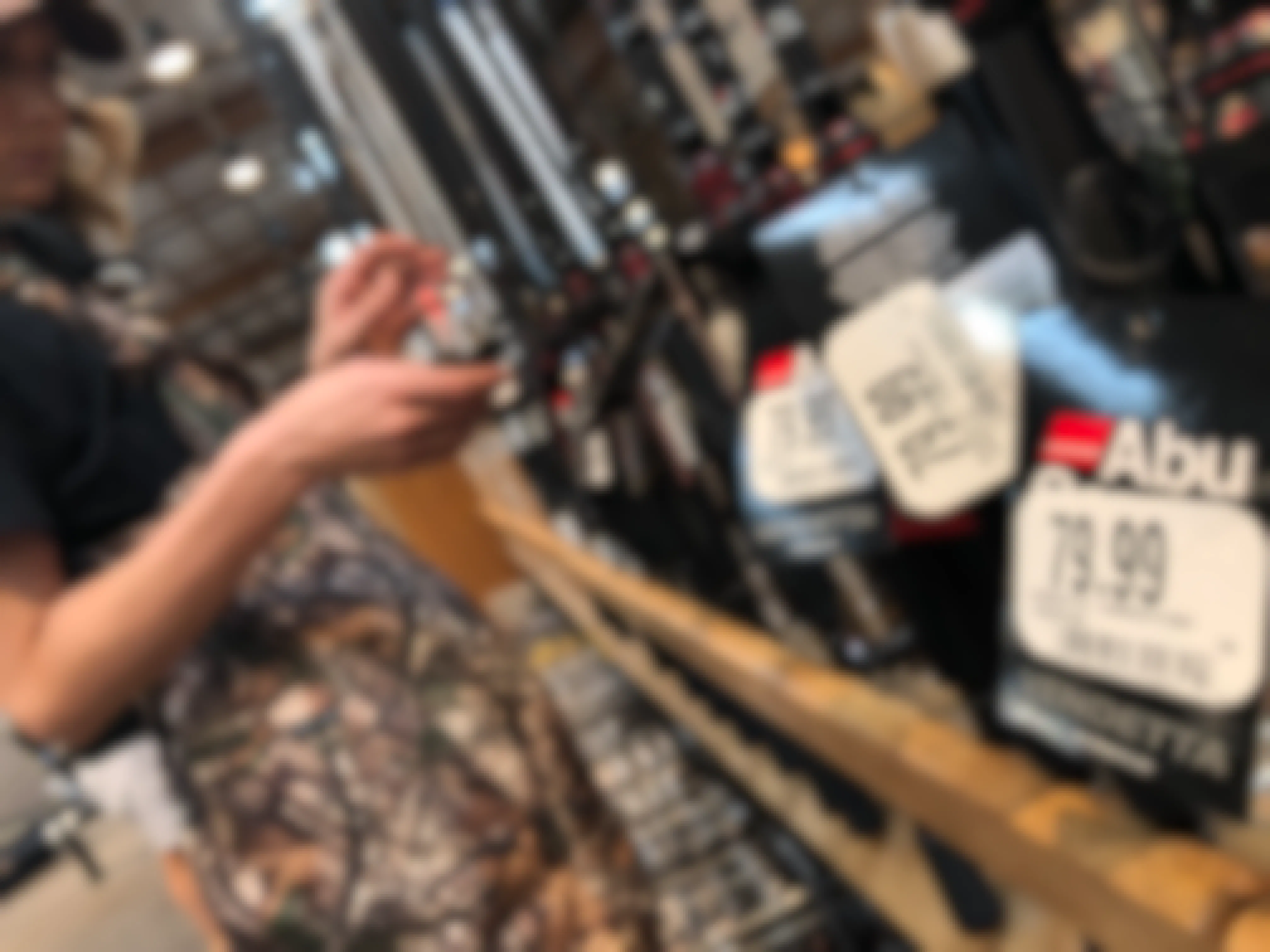 A person looking at fishing rods inside Cabela's, with white price tags in focus.