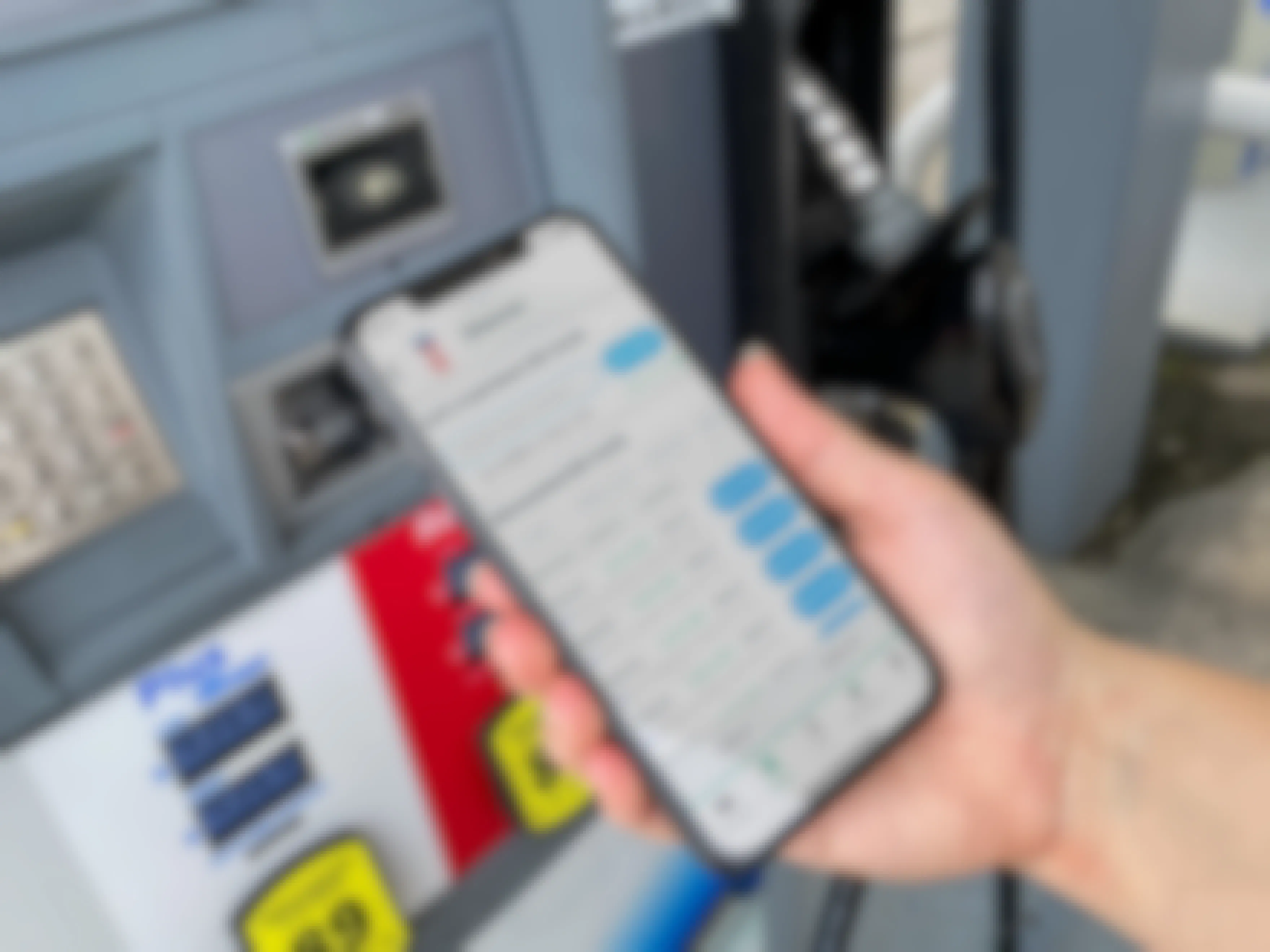A person holding their phone displaying the Raise discount gift card app in front of a gas pump.