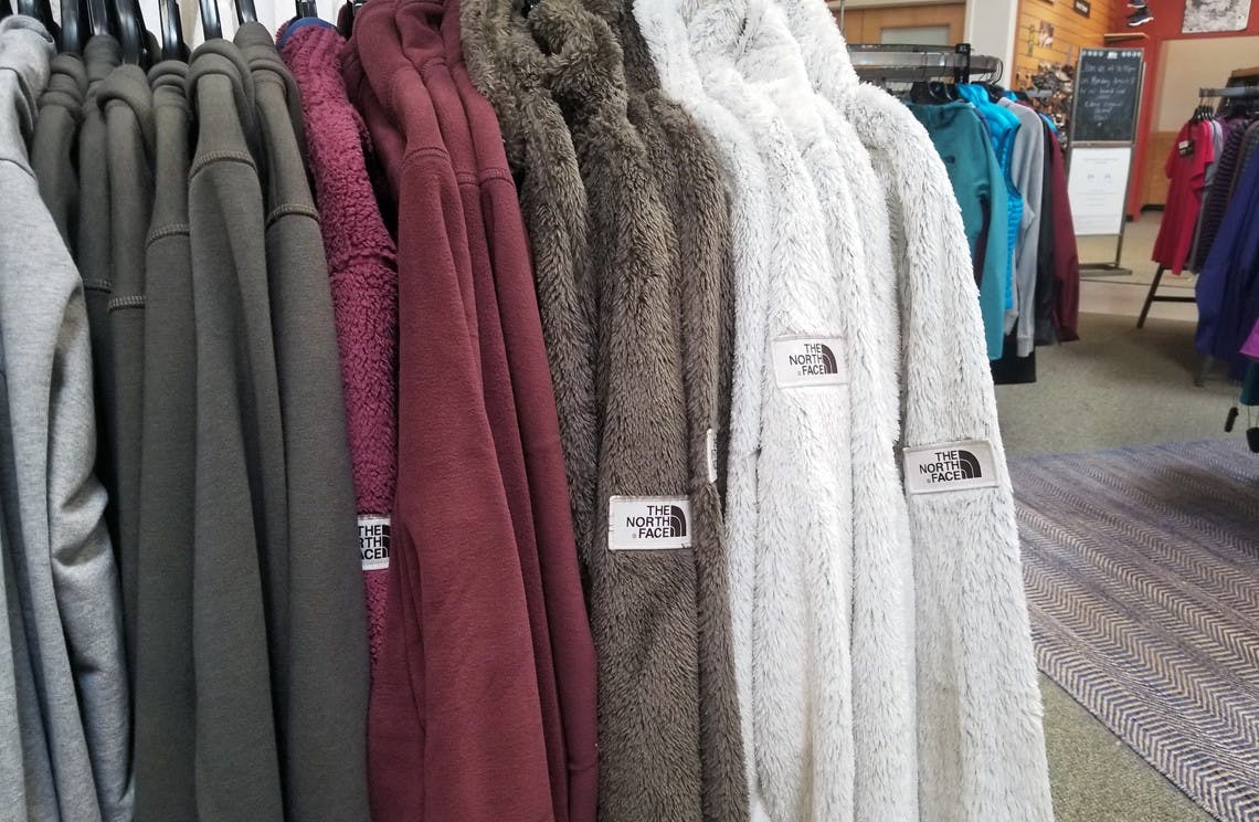 collection of north face fleece zip up jackets hanging on a rack