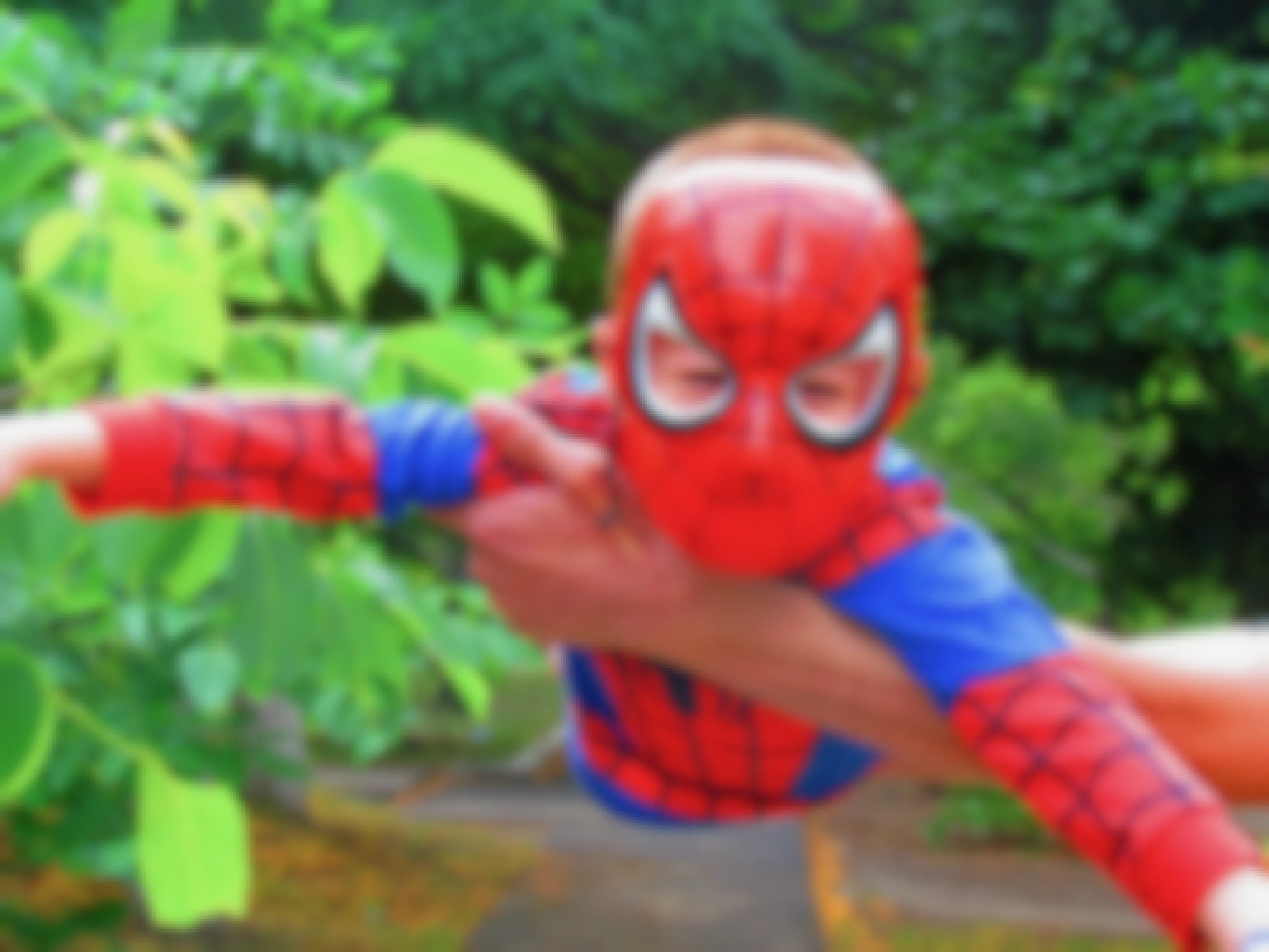 A child dressed as Spider-Man being held in the air.