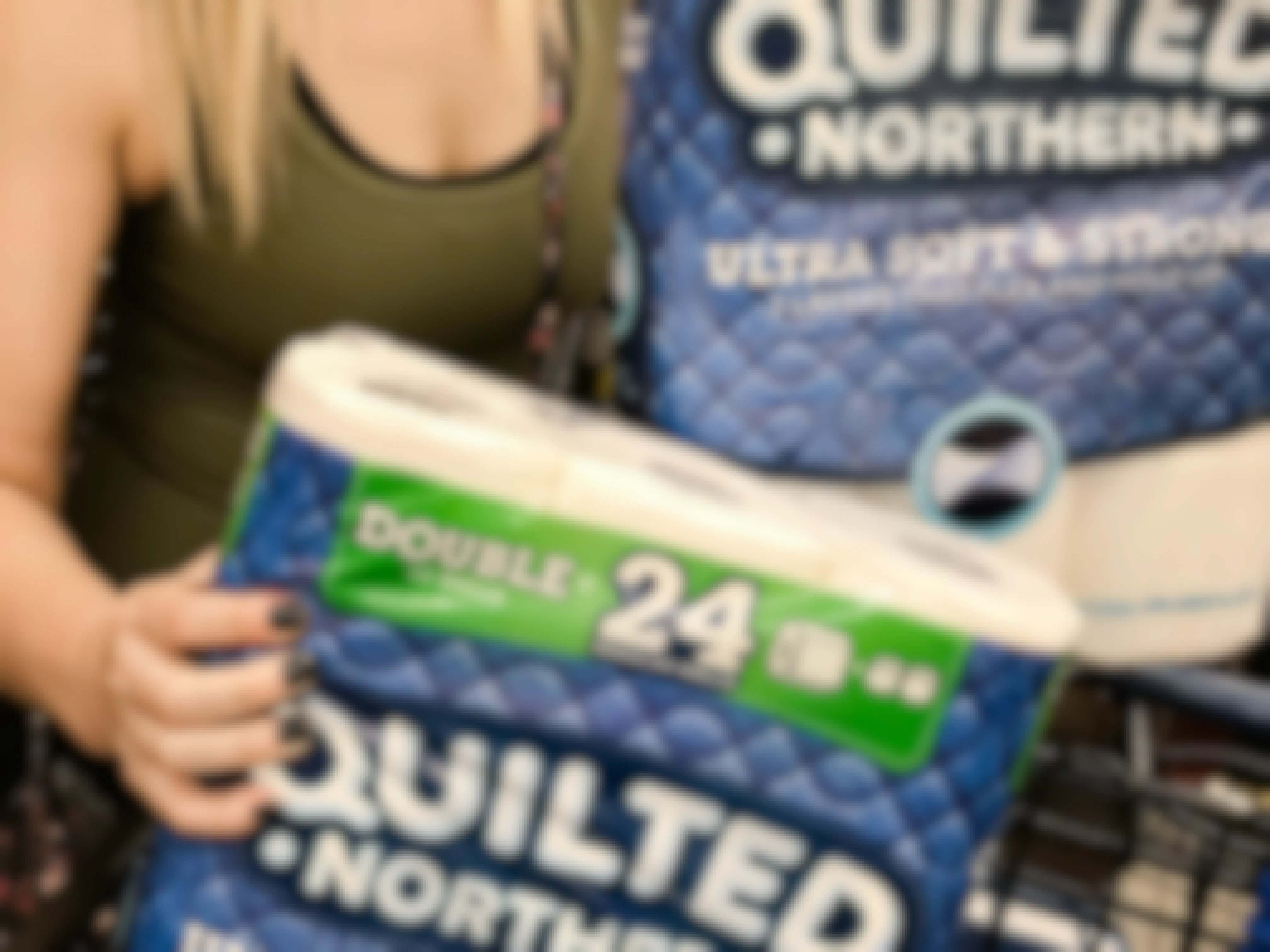 Woman holding two packs of Quilted Northern toilet paper