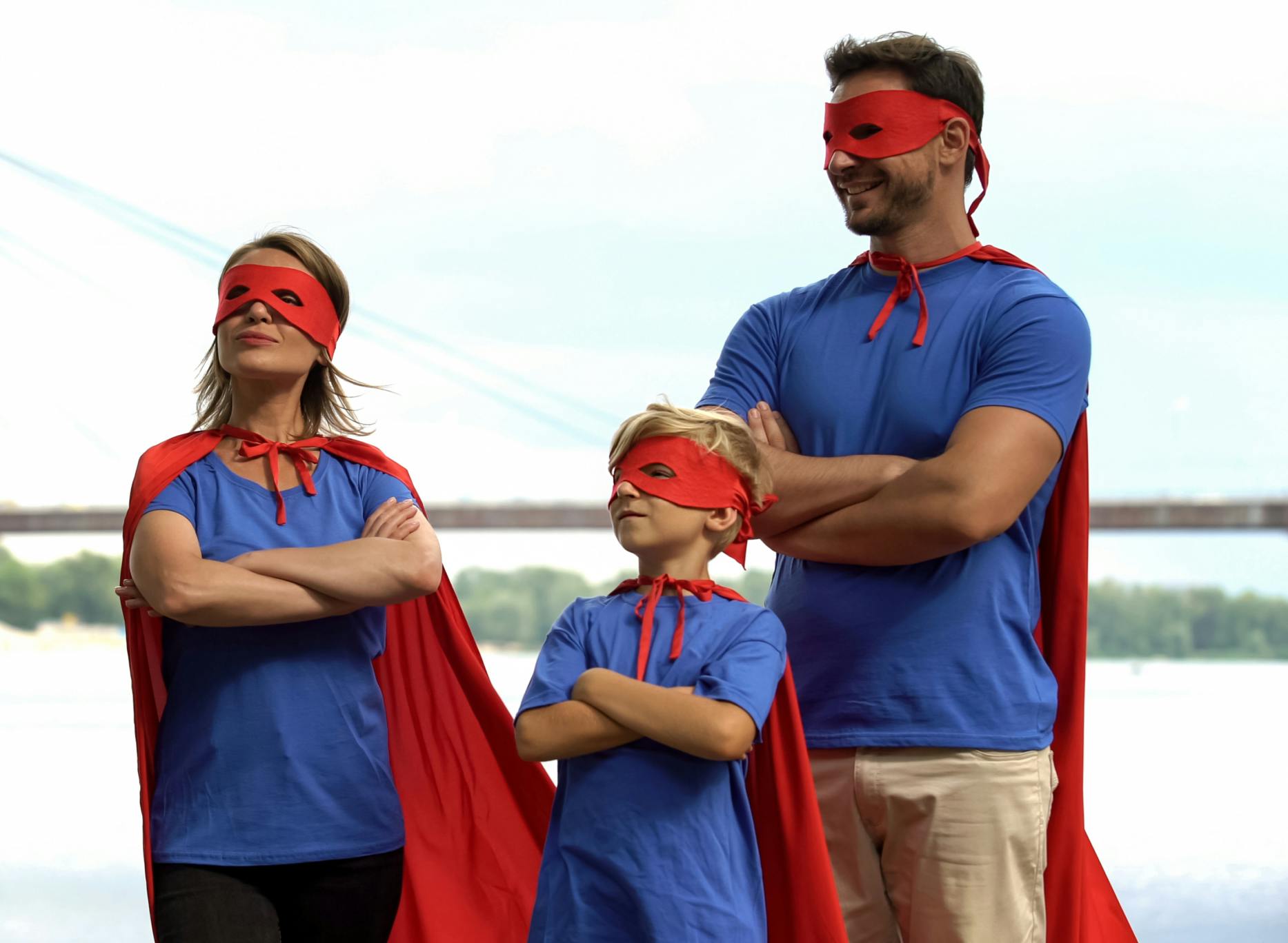 A family standing together dressed as super heroes striking a power pose.