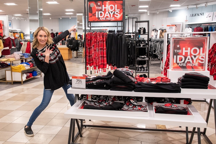 woman at Macy's next to holiday sign