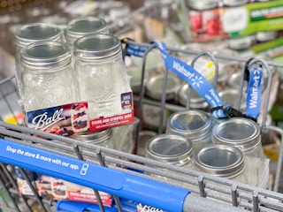Several 4-packs of Ball canning jars filling a Walmart shopping cart basket.