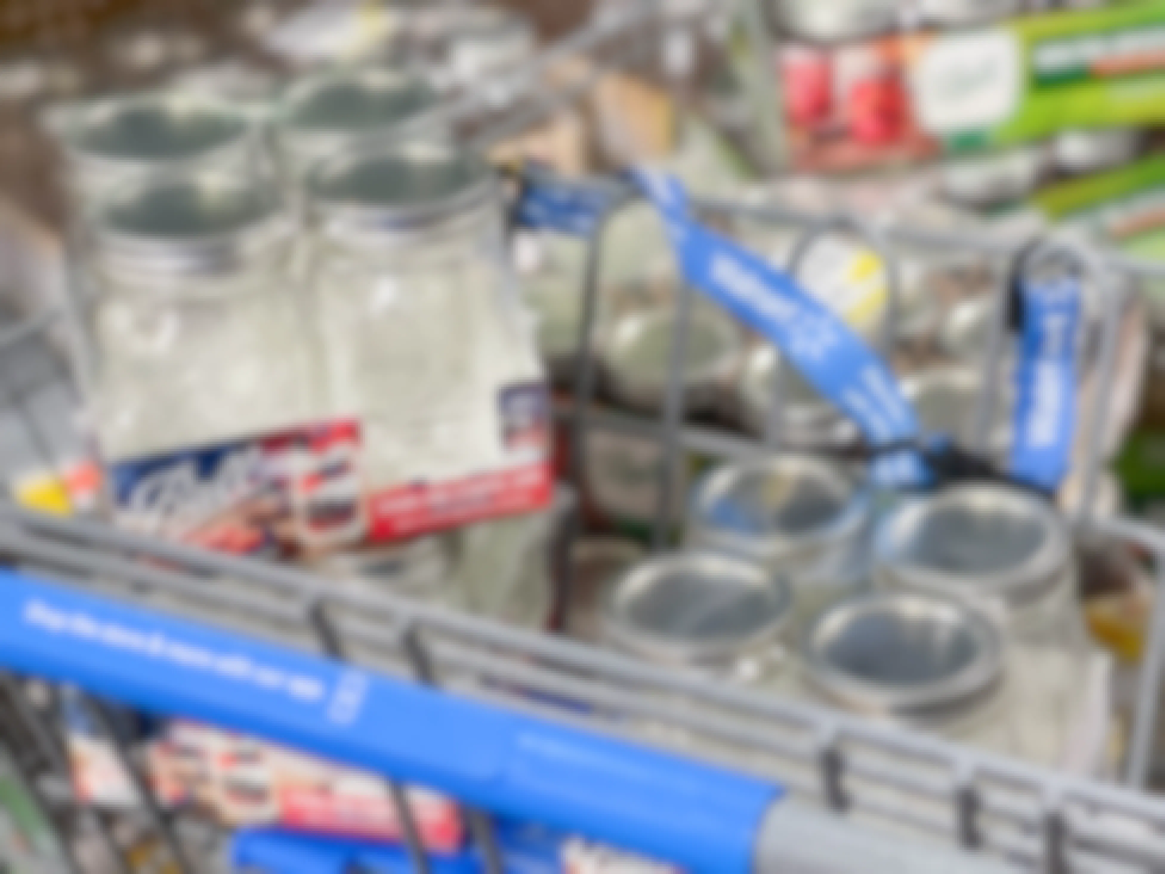 Several 4-packs of Ball canning jars filling a Walmart shopping cart basket.