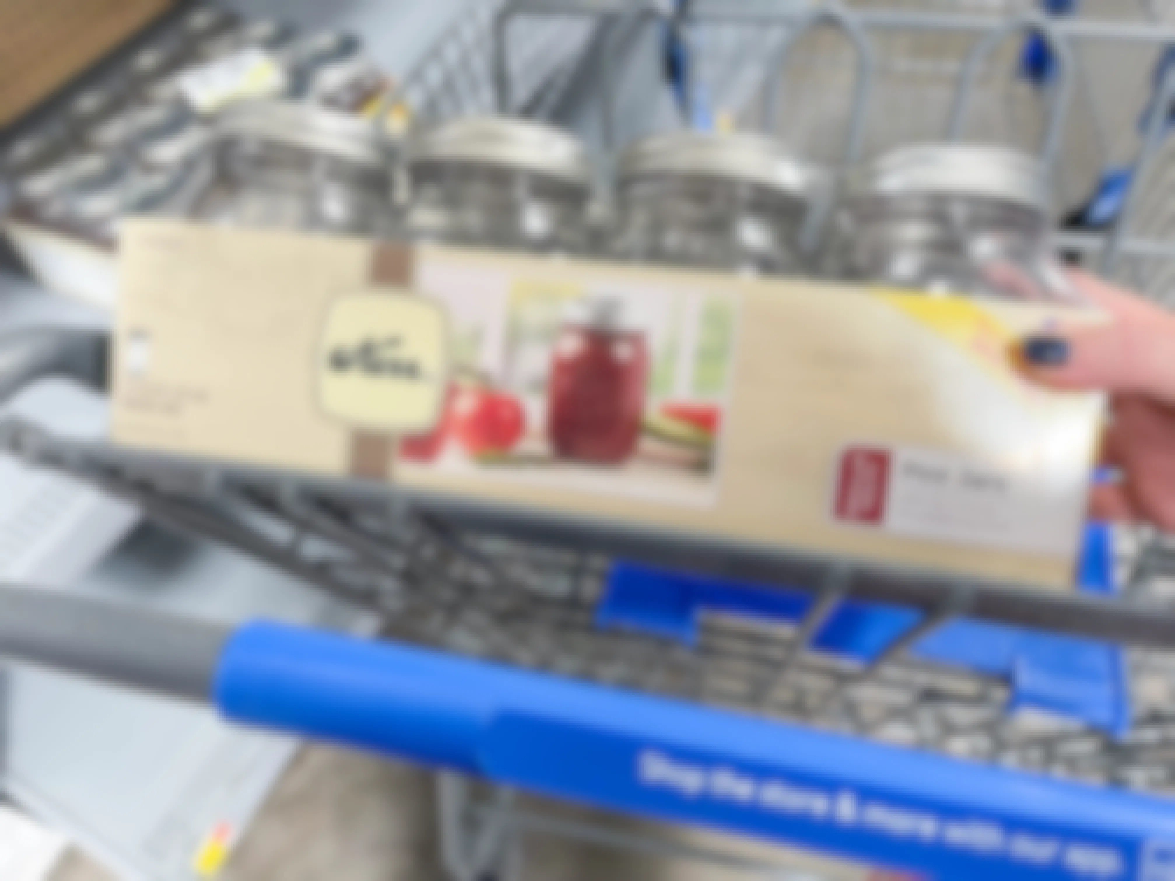 A case of Kerr canning jars being placed into a Walmart shopping cart basket.