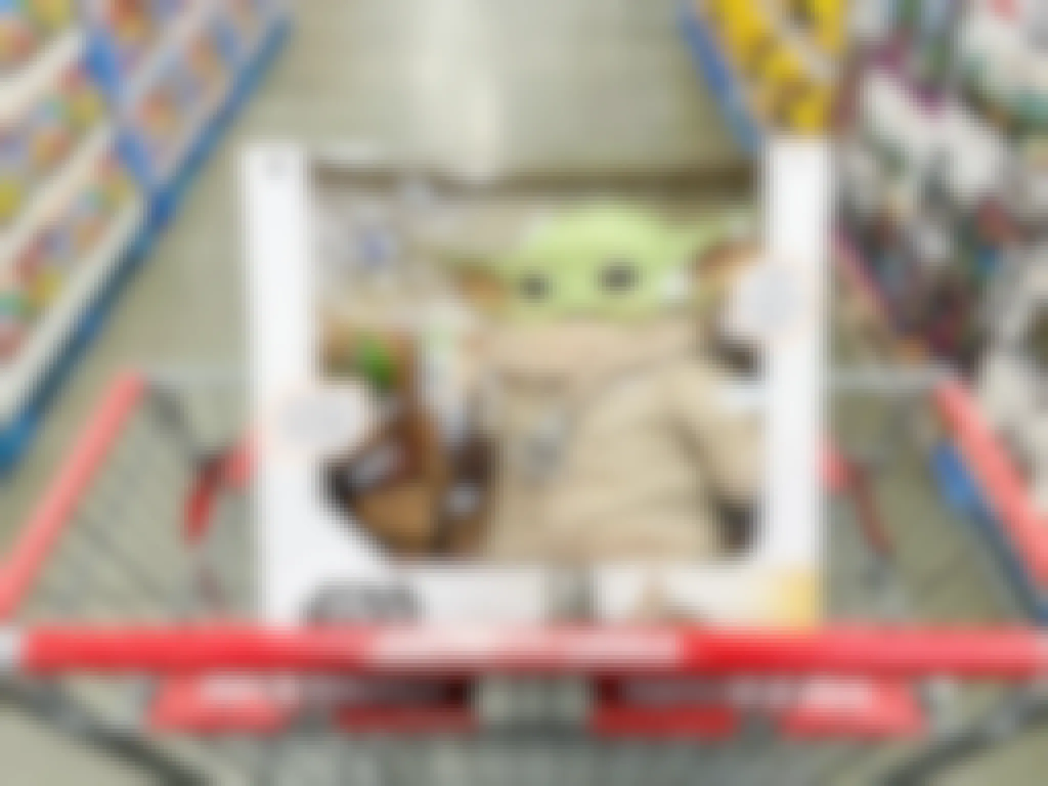 A Star Wars Yoda toy in the basket of a Costco shopping cart parked in the toy aisle at Costco.
