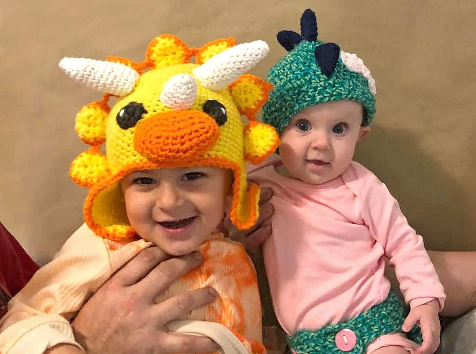 Two children children wearing crocheted dinosaur hats