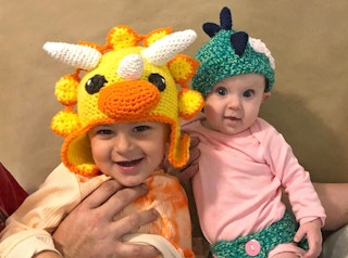 Two children children wearing crocheted dinosaur hats