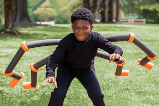 A child dressed as a spider with pool noodles for legs