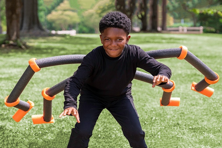 A child dressed as a spider with pool noodles for legs