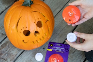 Battery operated tea lights held next to a pumpkin