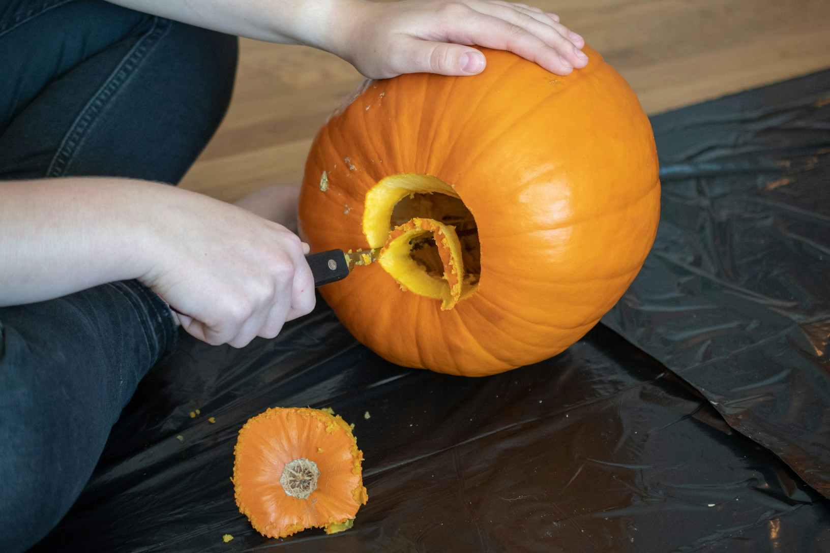 Person carving a hole into a pumpkin