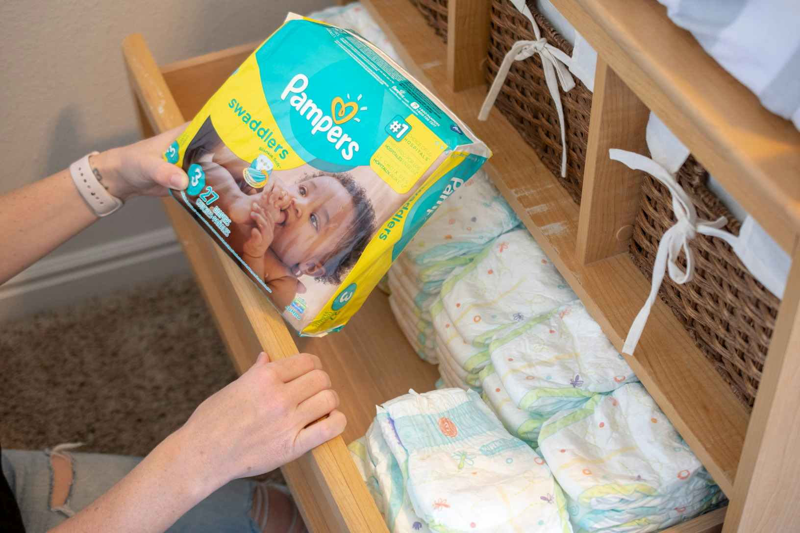 person holding pack of Pampers diapers near drawer