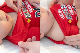 person pulling bodysuit down from baby's shoulders