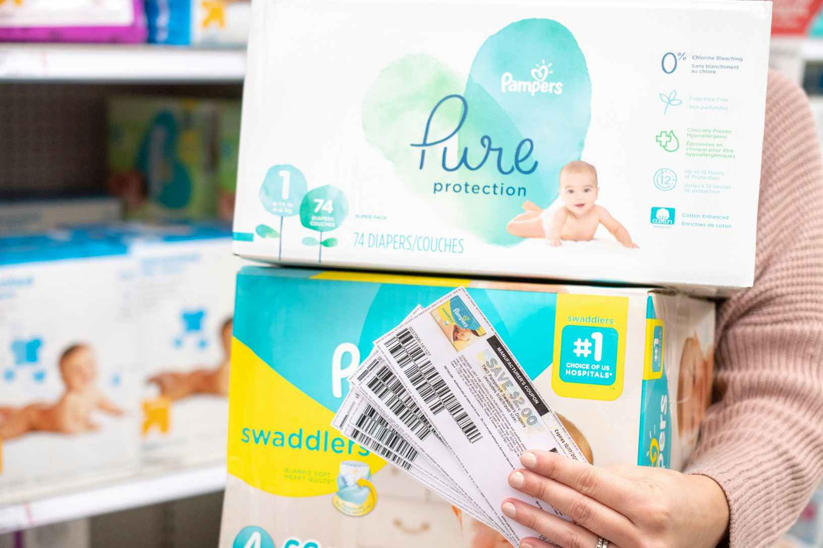 person in store holding boxes of Pampers diapers and coupons