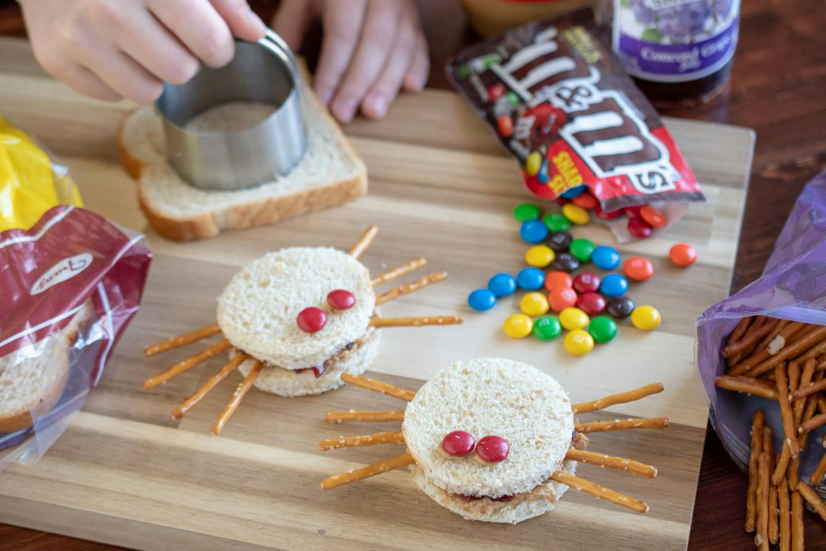 Sandwiches cut in circles with pretzel sticks and m&m's on them to make them look like spiders.