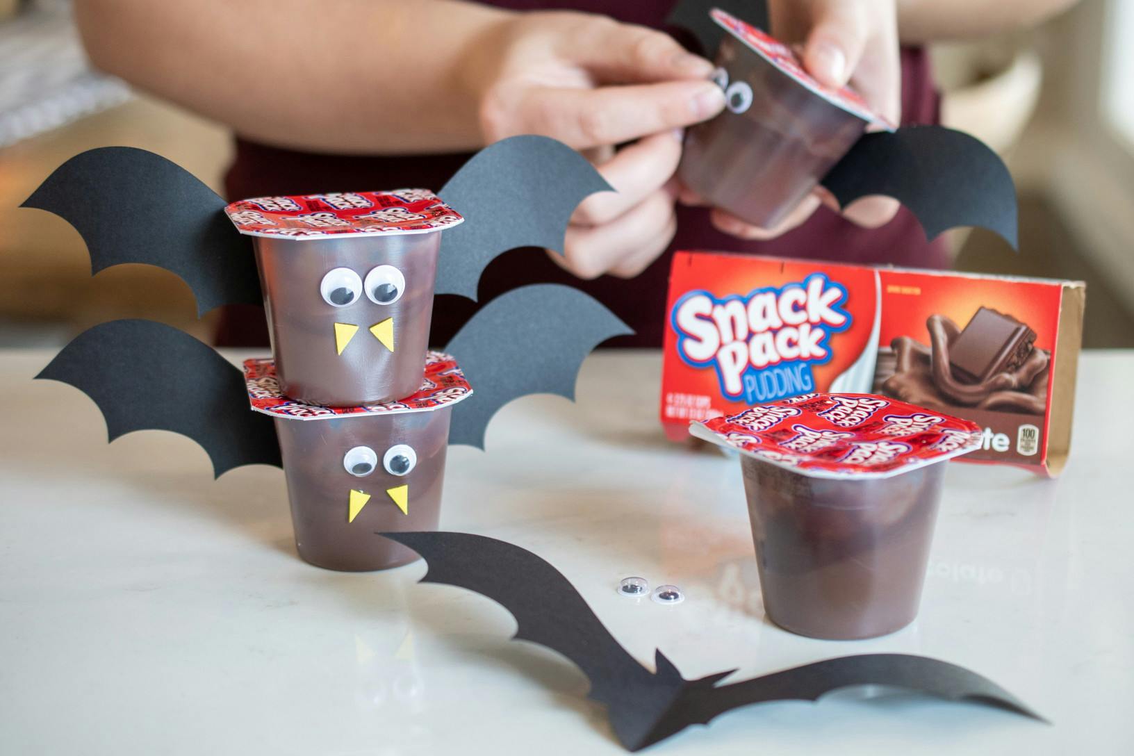 Chocolate pudding cups decorated to look like little bats with with googly eyes, construction paper bat wings, and yellow foam triangles for fangs.