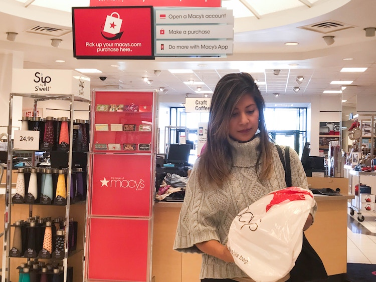 a woman holding a Macy's bag after checking out while holiday shopping at Macy's