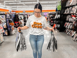 a person holding up spirit halloween costumes