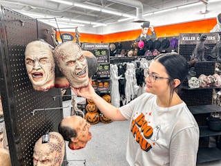 a person holding up a spirit halloween zombie head