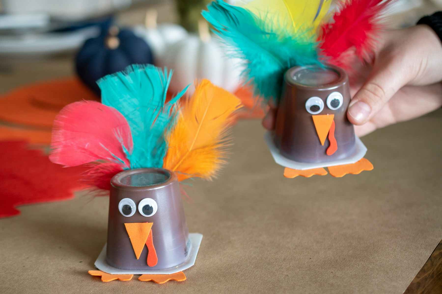 Chocolate pudding cups made to look likeThanksgiving turkey with googly eyes, and colorful feathers.