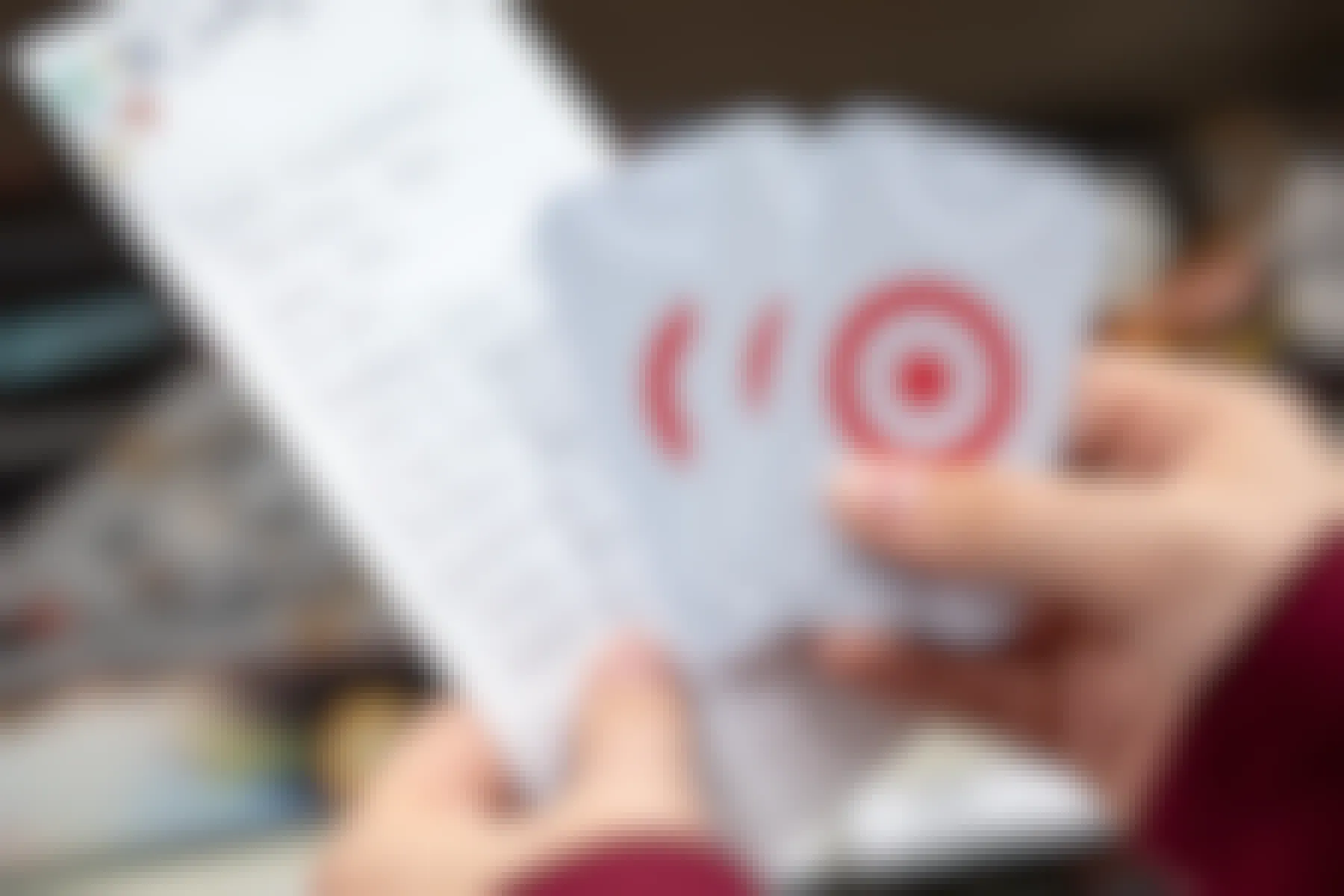 A person holding some Target gift cards and a handwritten Christmas wishlist
